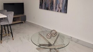 Ein modernes Wohnzimmer mit Glastisch, Flachbildfernseher und Stadtbild an der Wand.