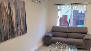 Ein modernes Wohnzimmer mit einem grauen Sofa, einem Glastisch und zwei Sesseln.
