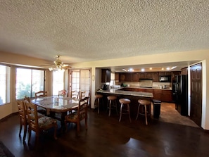 A spacious kitchen with a central island, wooden chairs, and a dining table.