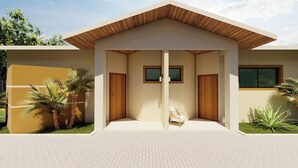 Een modern gebouw met een plat dak, twee houten deuren en een klein zitgedeelte met een stoel en een tafel.