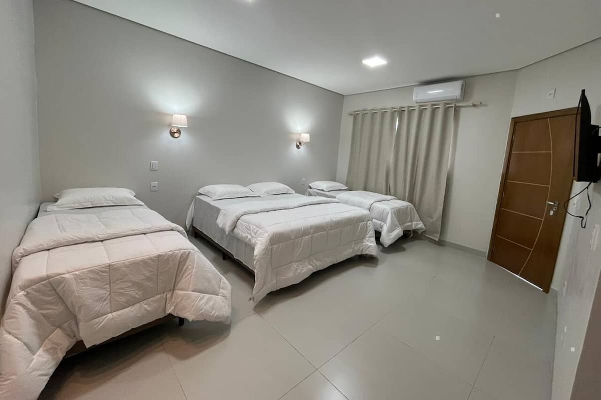 A room with three beds, a ceiling fan, and an air conditioning unit.