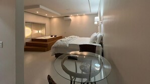 Een moderne slaapkamer met een bed, een glazen tafel en een inbouwschrank.