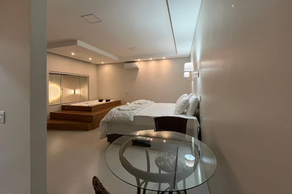 A modern bedroom with a bed, a glass table, and a built-in bench.
