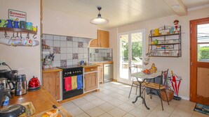 Eine Küche mit Herd, Backofen und Spüle, Holzschränken und einem Essbereich mit Tisch und Stühlen.