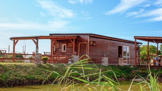 Eine rustikale Holzhütte mit Veranda, gelegen am Wasser.