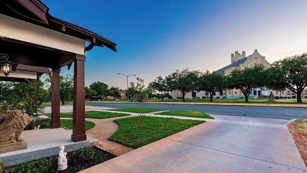 A covered outdoor area with a statue, a building with a distinctive roof, and a clear sky. - Royal Estate Maison Entiere de Luxe (Abilene)