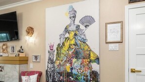A room with a large abstract painting, a television, a lion head sculpture, and a framed picture on the wall. - Royal Estate Maison Entiere de Luxe (Abilene)