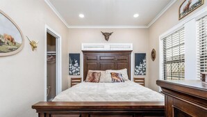 A bedroom with a large bed, a wooden headboard, and a decorative bull head above the bed. - Royal Estate Maison Entiere de Luxe (Abilene)