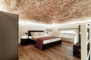Ein Schlafzimmer mit einem Zargenholzbodenmuster an der Decke, einem Bett mit roter Decke, einem Nachttisch mit Lampe und einer Korbsitzbank.