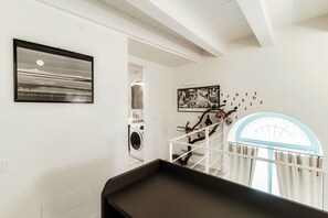 Un interior limpio y moderno con una obra de arte enmarcada, una escalera con barandilla y una zona de lavandería.