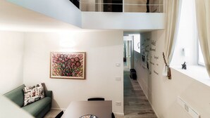 A modern interior with a green sofa, a dining table, and a staircase leading to an upper level. - Diaz 8 - MyHomeinComo (Como)