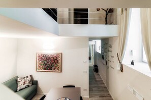 A modern interior with a green sofa, a dining table, and a staircase leading to an upper level. - Diaz 8 - MyHomeinComo (Como)