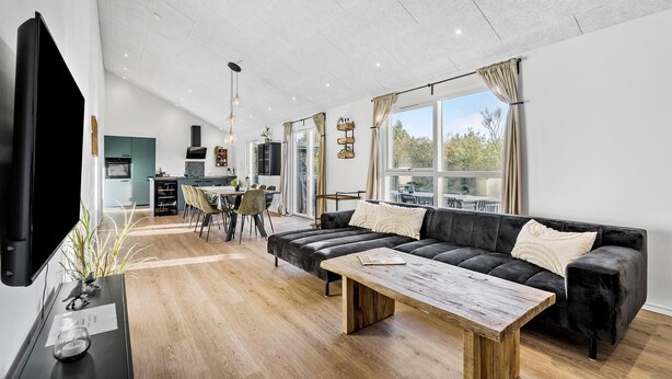 Una sala de estar moderna con un sofá de cuero negro, una mesa de centro de madera y un televisor de pantalla plana montado en la pared.