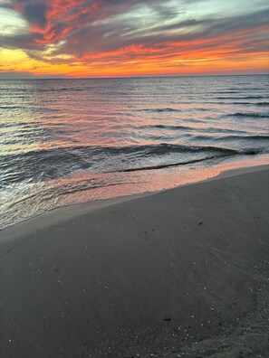 A beach with a sunset over the ocean.