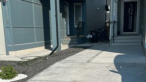 A residential street with houses on both sides, a concrete sidewalk, and a clear sky. - Cozy and Private Suite - Free On-Prem Parking & PS5 Available (Calgary)