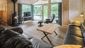 Een gezellige woonkamer met een houtkachel, een bank, een salontafel en een televisie.