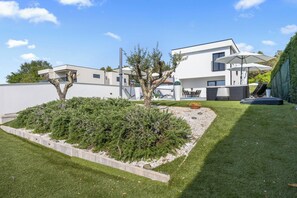 Ein modernes, zweistöckiges Haus mit Swimmingpool, Sitzgelegenheit im Freien und einem gepflegten Garten.