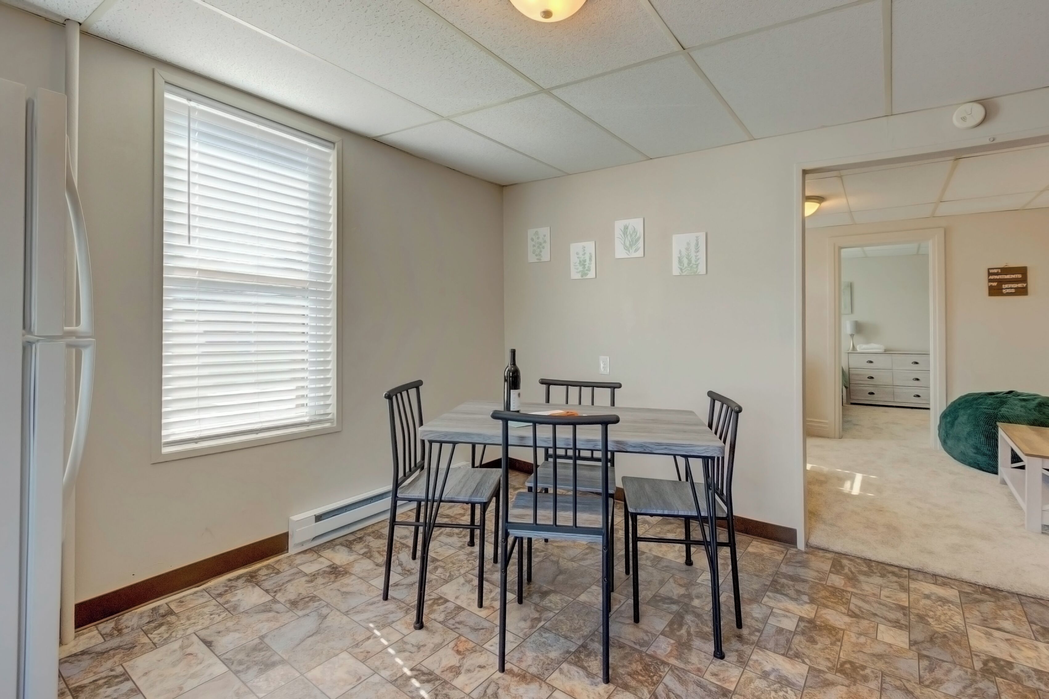 Un coin repas avec une table et des chaises, une fenêtre avec des stores et un radiateur.