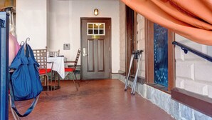 Un espace extérieur abrité, avec une table et des chaises, une porte et des béquilles appuyées contre le mur.