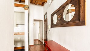Un pasillo con un banco de madera, un espejo y un piso de baldosas.