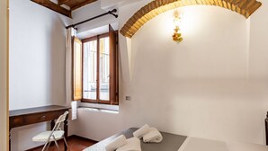 Un dormitorio con cama, escritorio, silla y ventana.