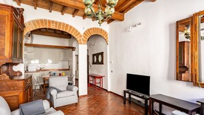 Una sala de estar con televisor, sofá y comedor con mesa y sillas.