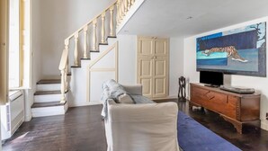 A staircase with wooden balusters, a beige door, a television on a wooden stand, and a painting on the wall. - GuestHost - House Overlooking the Harbour (Trani)