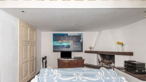A bedroom with a bed, a television, a fireplace, and a painting on the wall. - GuestHost - House Overlooking the Harbour (Trani)