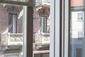 A view through a window of a building with ornate balconies and a brick facade.