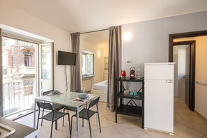 A compact living space with a dining table, chairs, a TV, a refrigerator, and a kitchenette.