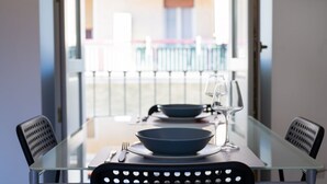 Une table à manger avec des chaises, une cloison en verre et une vue sur un balcon.