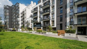 A modern apartment building with multiple balconies, a well-maintained lawn, and a bench. - Bemowo Narwik Deluxe Studio (Warszawa)