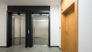 An elevator with a digital display and a wooden door to the right. - Bemowo Narwik Deluxe Studio (Warszawa)