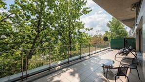 A balcony with a glass railing, a table, and two chairs.