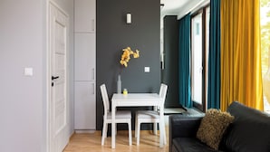 A modern living space with a dining area, a sofa, and a window with curtains.