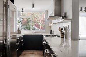 Eine moderne Küche mit großem Fenster, Edelstahlgeräten und minimalistischem Design.