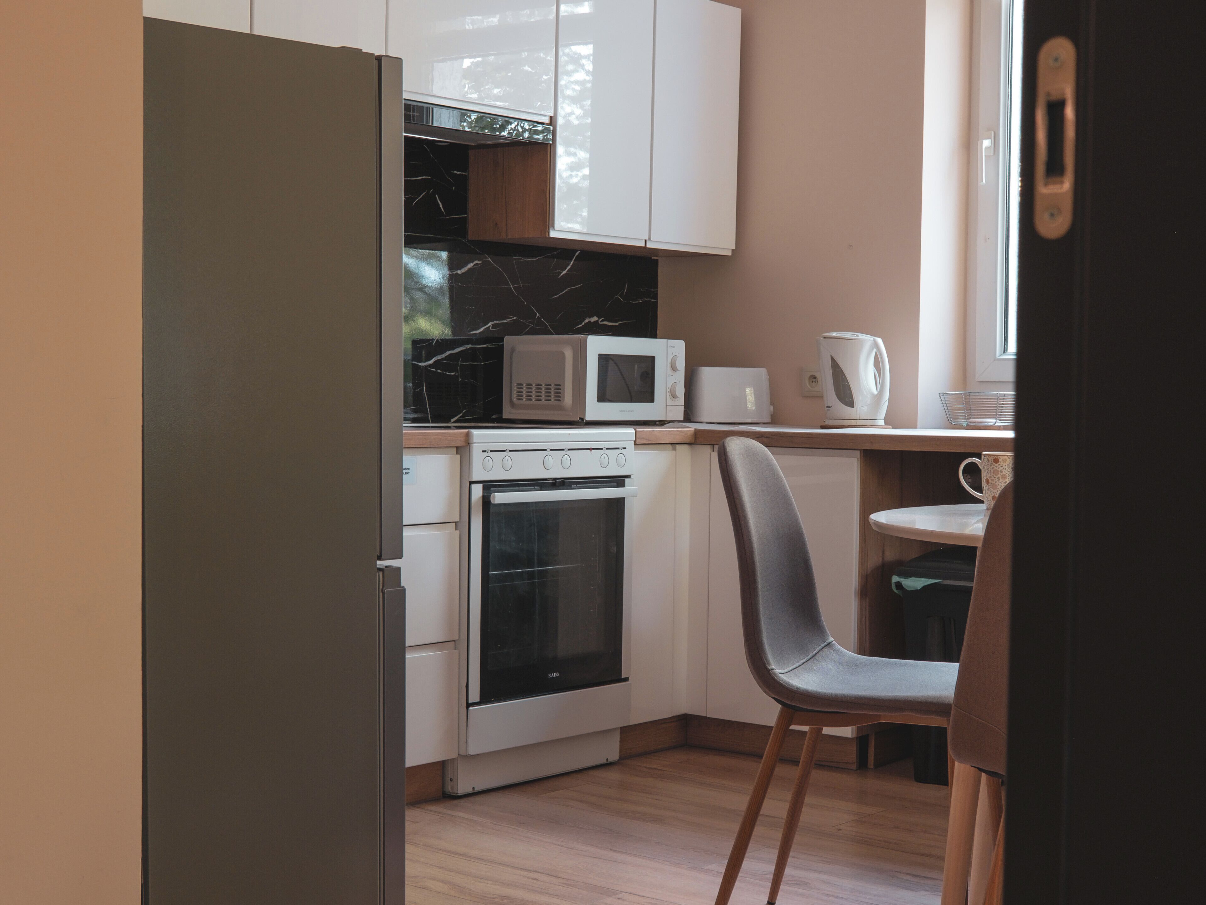 A compact kitchen with white cabinets, a microwave, a toaster, and a kettle.