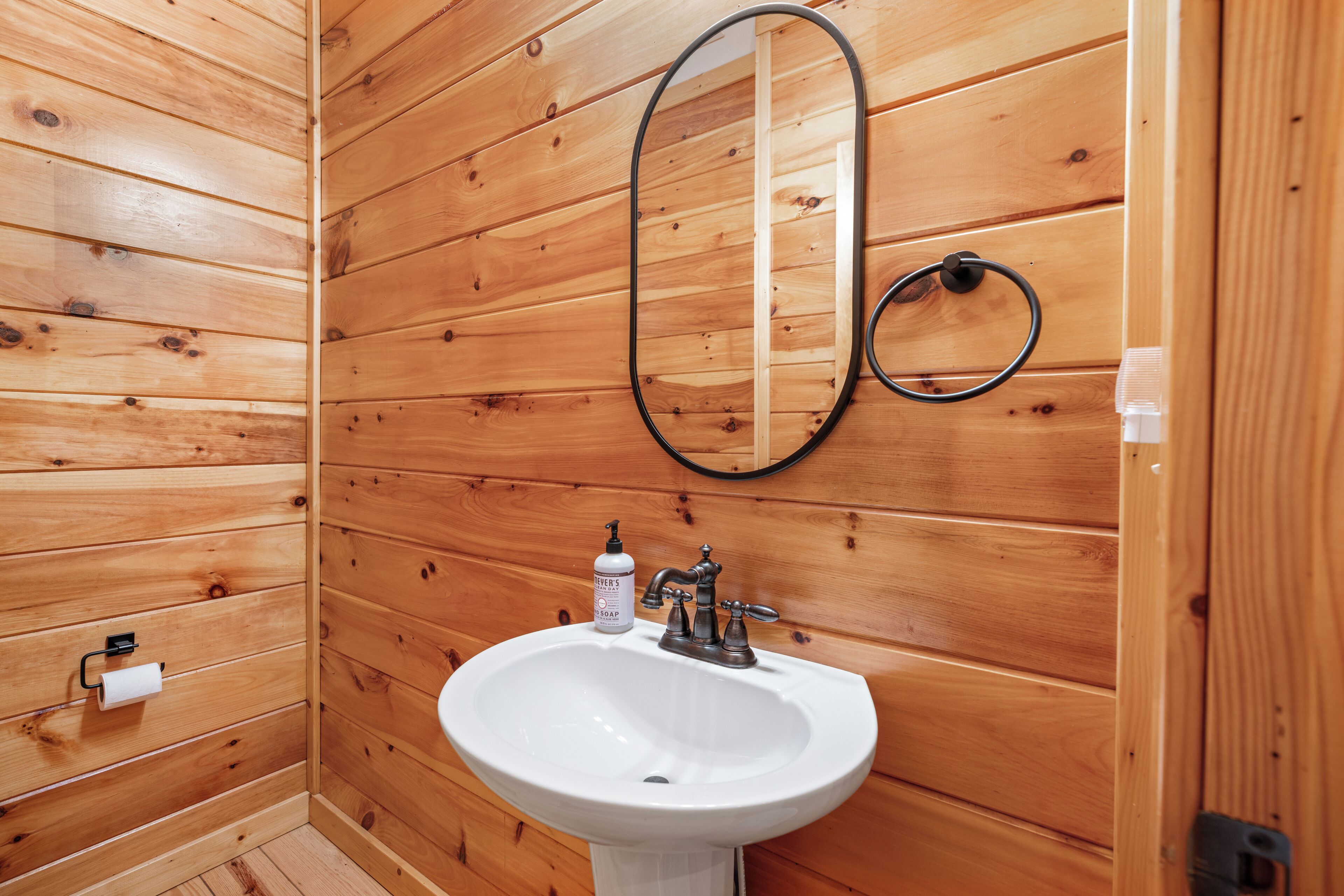 A simple white sink, accented by a round mirror above. 