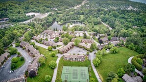 An aerial view of a residential area with houses, a tennis court, and a lake. - Chetola: Holly 4 - Condo near Downtown Blowing Rock! (Blowing Rock)