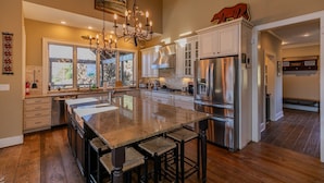 A spacious kitchen with a large island, stainless steel appliances, and a chandelier. - Robin Hoods Retreat - Luxury home, walk to river, hot tub, fire pit! (Jefferson)