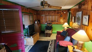 Een gezellige woonkamer met een televisie, een bank, een salontafel en een vloerkleed met vismotieven.