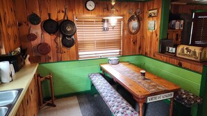 Een keuken met houten wanden, een groene bank, een houten tafel en een klok aan de muur.