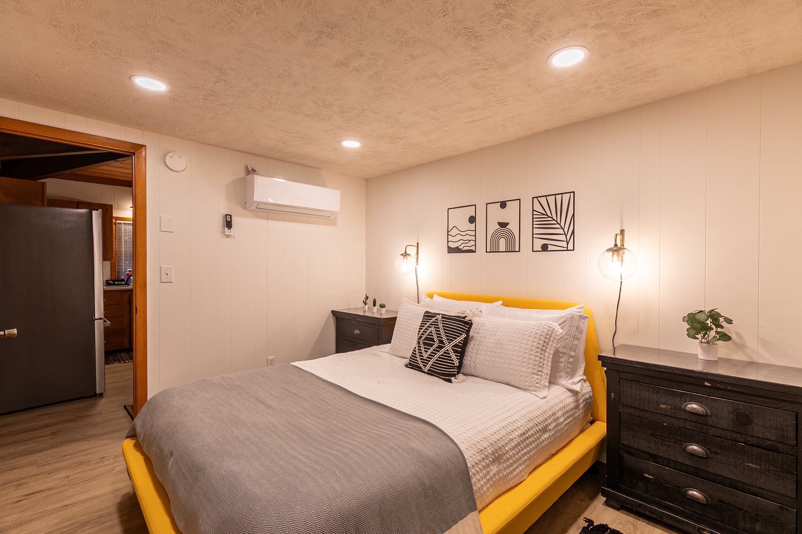 Une chambre à coucher comprenant un lit, des tables de chevet, une commode et des œuvres d’art accrochées au mur.