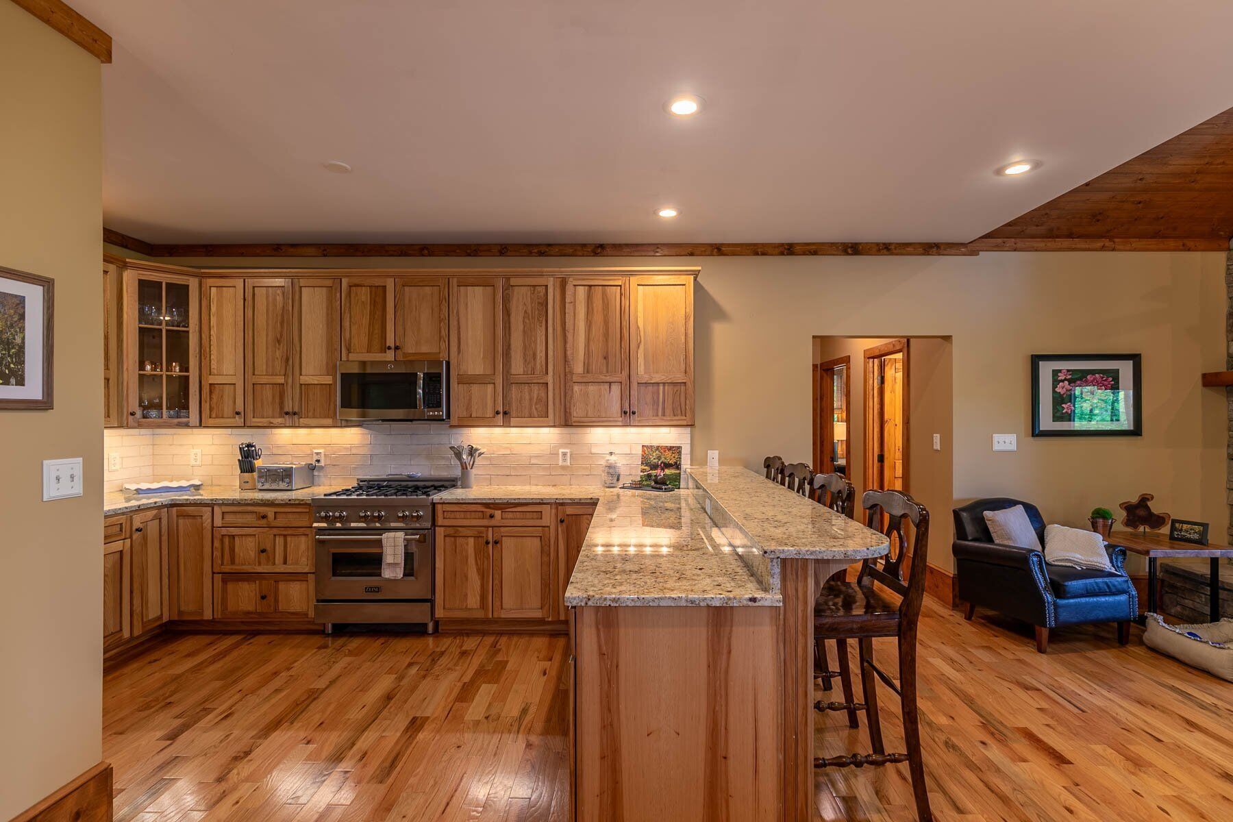 A spacious kitchen with wooden cabinets, a central island, and a dining area with chairs.