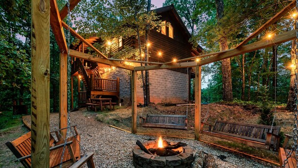 Ein rustikaler Außenbereich mit Feuerstelle, Holzbanken und einer Holzterrasse.