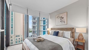 Une chambre d’hôtel moderne avec un grand lit, une vue sur la ville et un balcon.