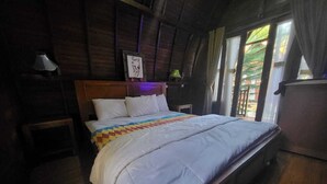 A bedroom with a wooden bed, a nightstand, a lamp, and a window with curtains. - Jambu Guest House  (Penida Island)