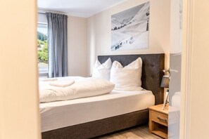 Un dormitorio moderno con cama, mesita de noche, lámpara y un cuadro en la pared.