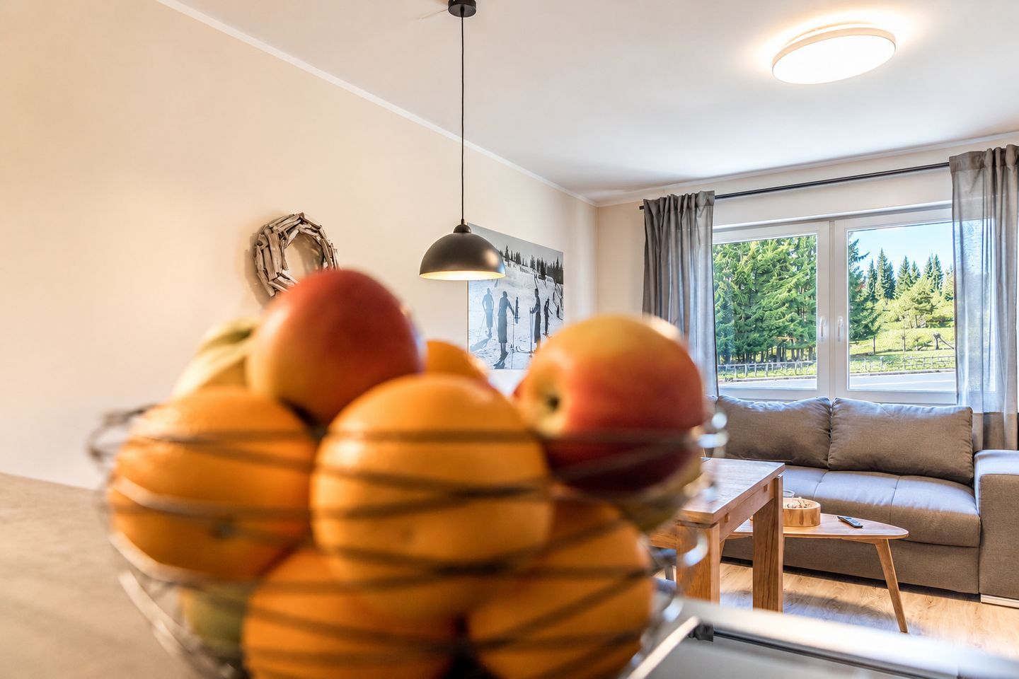 A living room with a sofa, a small table, and a fruit bowl on a table.