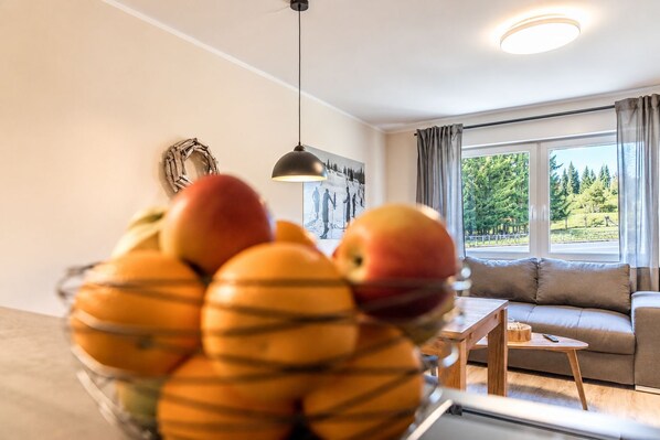 A living room with a sofa, a small table, and a fruit bowl on a table.
